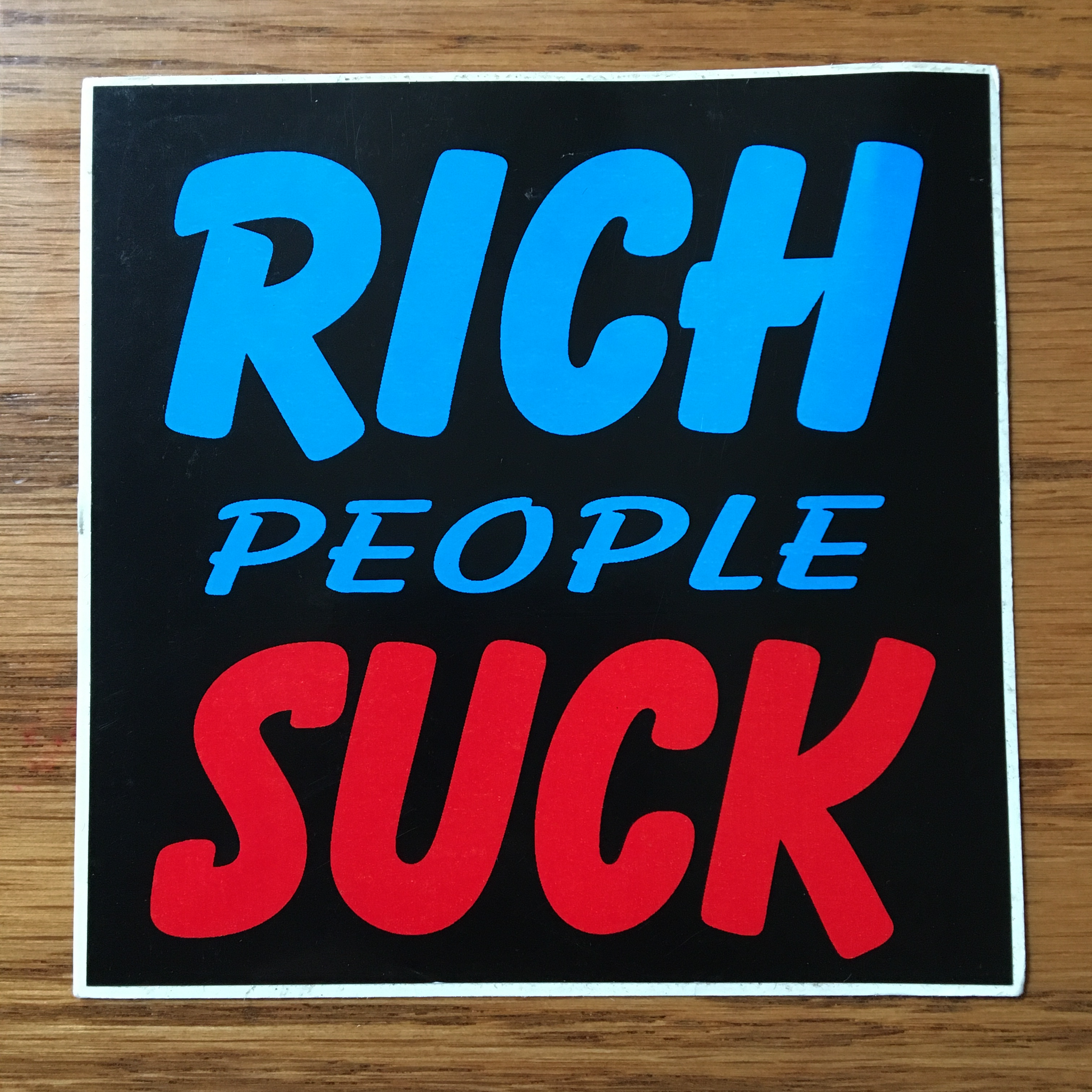 rich people suck 4" sticker black background with blue and red writing